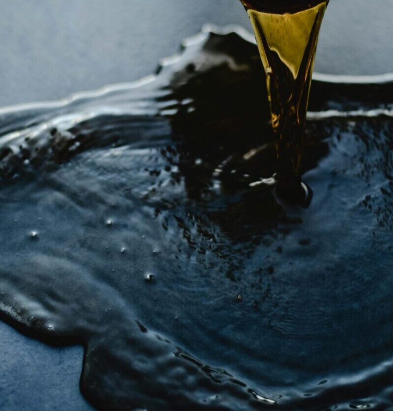 Close-up of red wine being poured and spilling on a dark surface, creating a dramatic scene.
